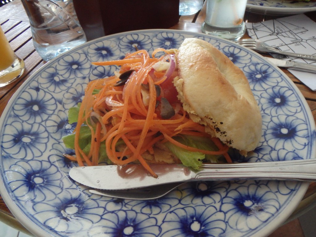 an incredible homemade bagel with hummus, carrot, and olives