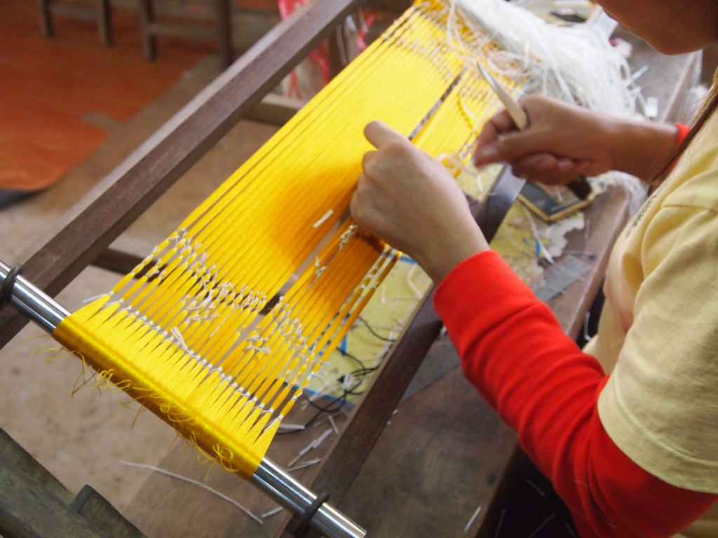 She is making the design using plastic bags. When she is finished the scarf will be dyed and then she'll start over for the next color. Depending on the design the thread may be dyed several times.